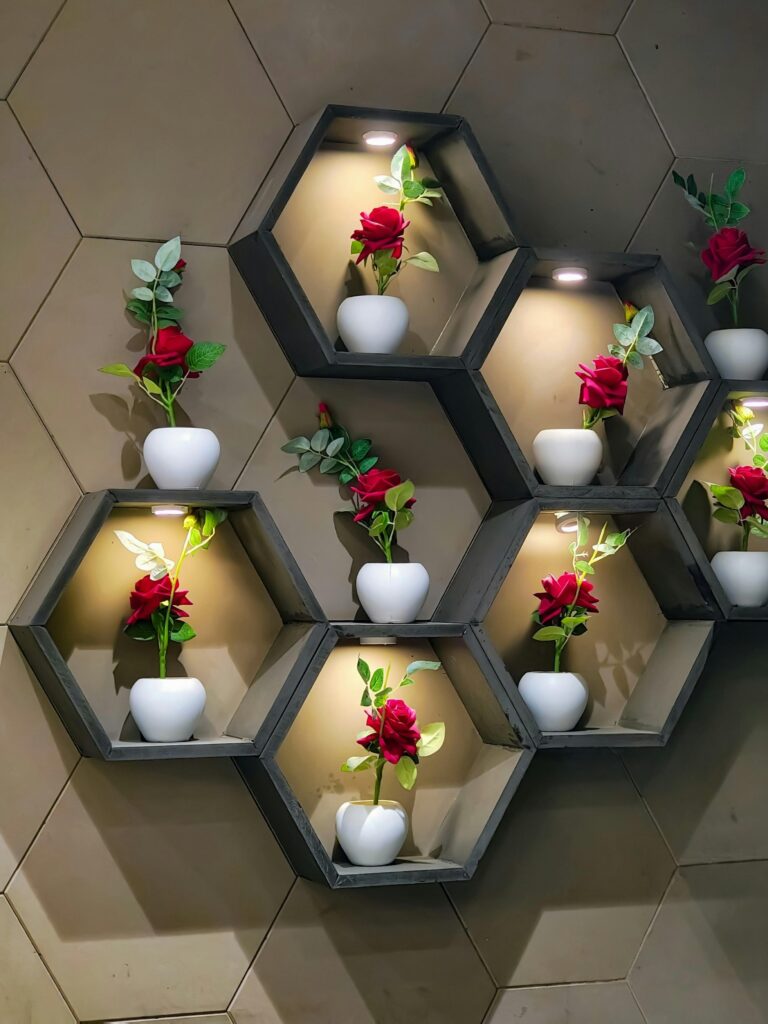 Aesthetic arrangement of red roses in white vases on hexagonal shelves with soft lighting.