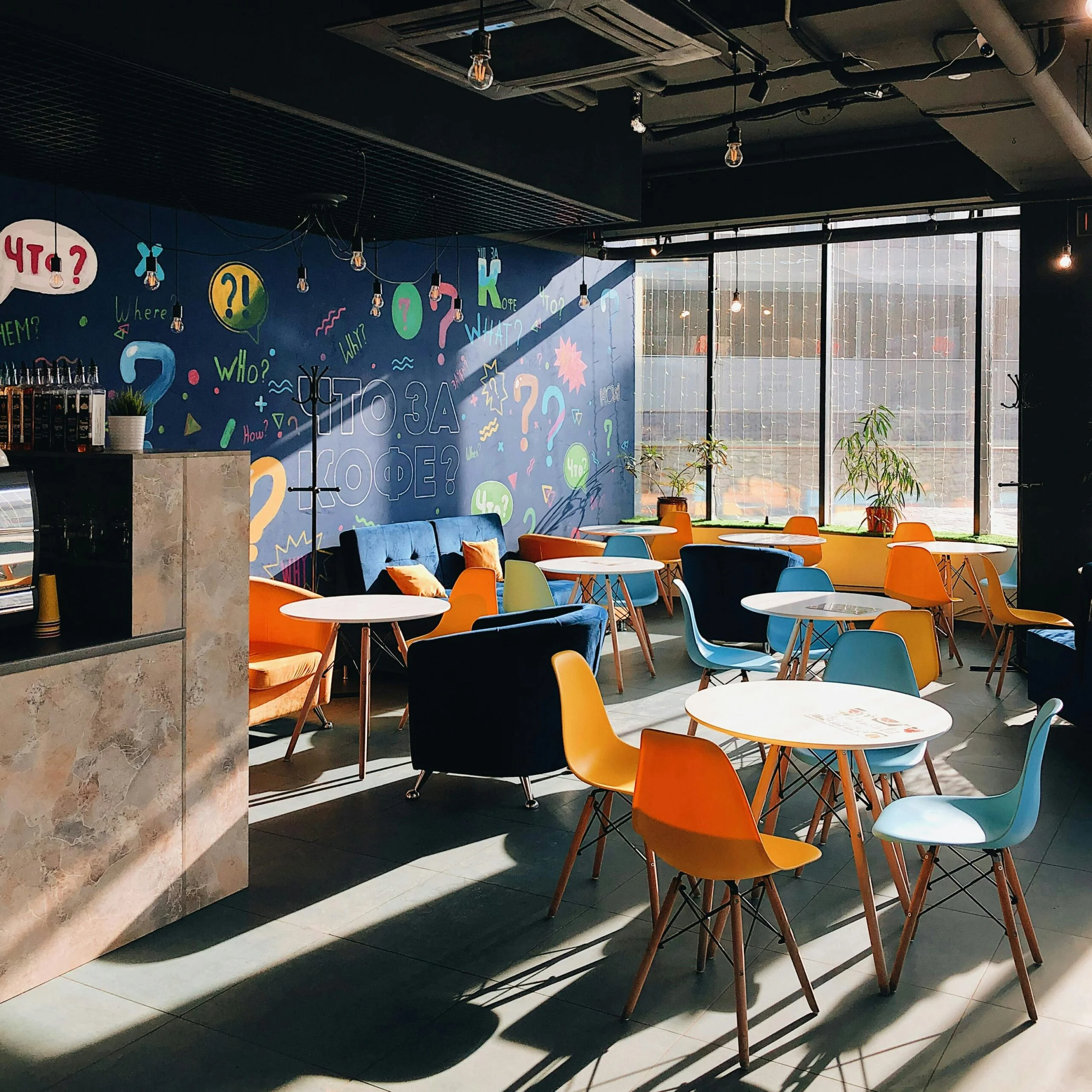 Vibrant café interior in Krasnoyarsk with colorful chairs, stylish décor, and artistic murals.